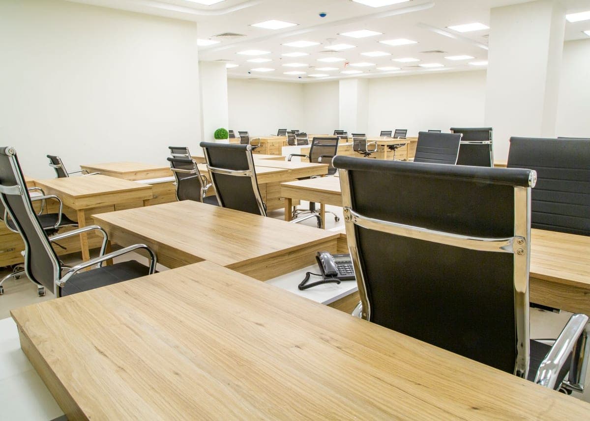 Plateau de bureaux en open space, postes et sièges alignés avant le passage d'entretien